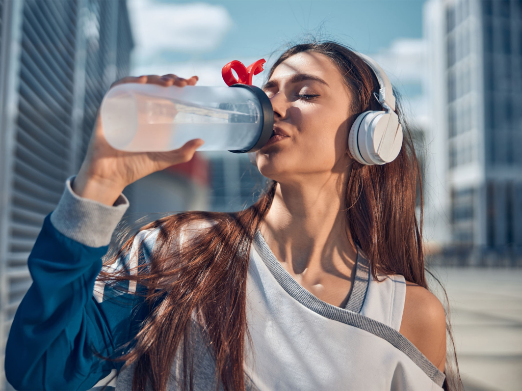 Frau trinkt Wasser aus einer Sportflasche