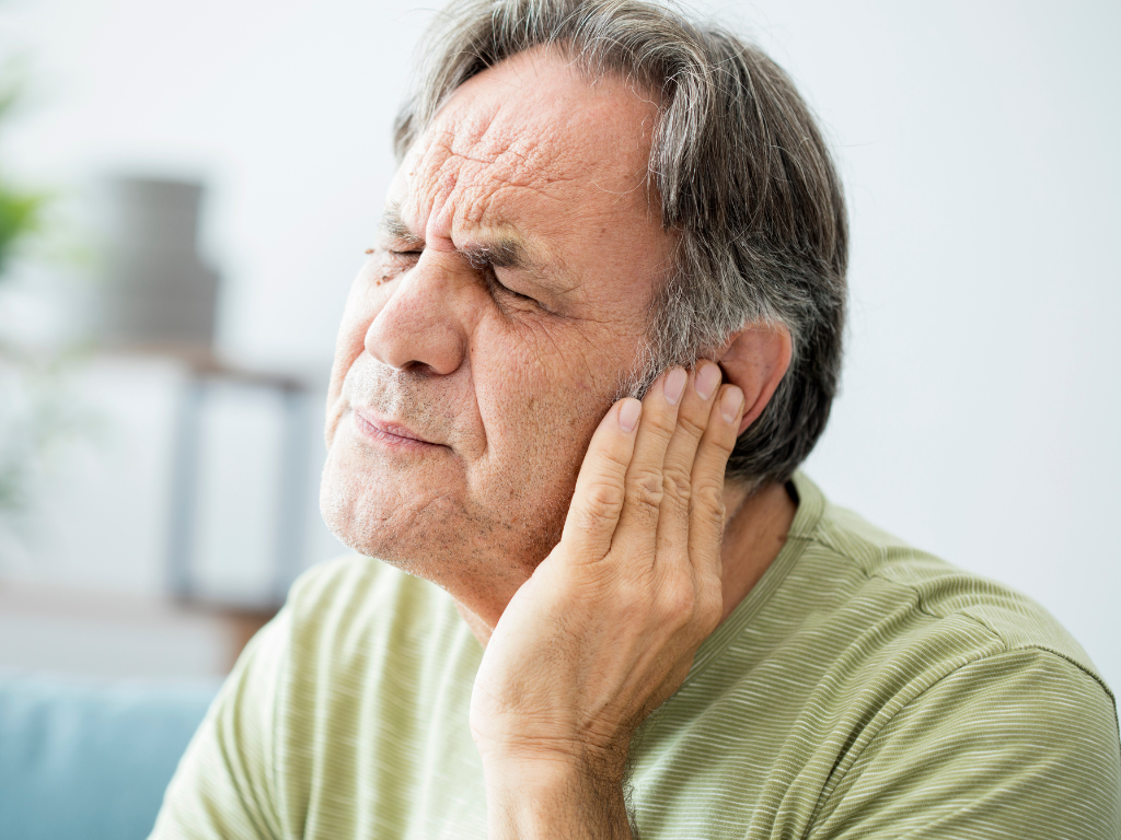 Foto eines Mannes, der sich das Ohr vor Schmerzen hält