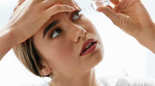 Trockene Augen Medikamente: Junge Frau benutzt Augentropfen.